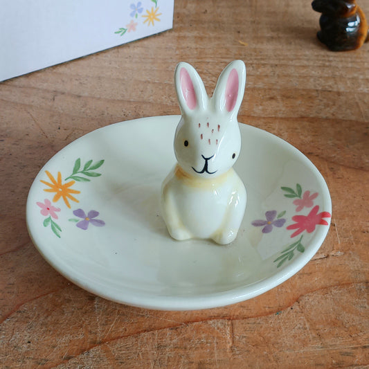 Add a charming touch of spring to your space with this Bunny Floral Ceramic Trinket Dish. Featuring a delicate floral design and a sweet bunny illustration at the center, this dish is perfect for holding jewellery, keys, coins, or other small treasures. Whether placed on a dresser, vanity, or bedside table, it combines functionality with fun and festive decor, making it an ideal gift or seasonal accent.