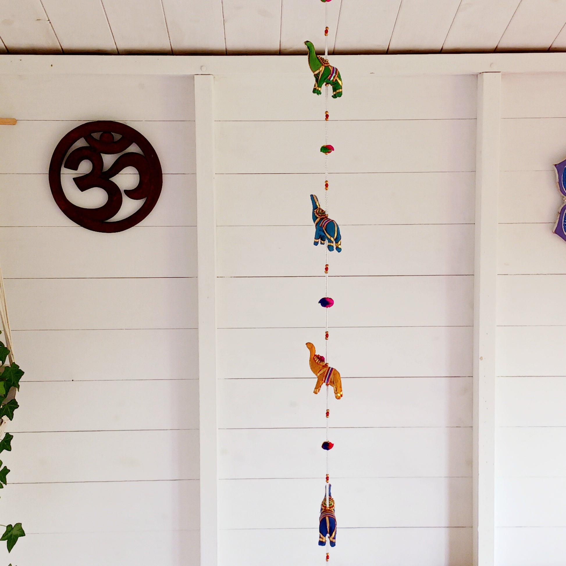 Bring vibrant charm and a touch of global-inspired décor into your home with this beautifully handcrafted stuffed elephant hanging garland. Designed in a traditional tota bell style, this decorative piece features a string of brightly coloured fabric elephants, carefully interspersed with playful beads, mini pom-poms, and delicate jingly bells.