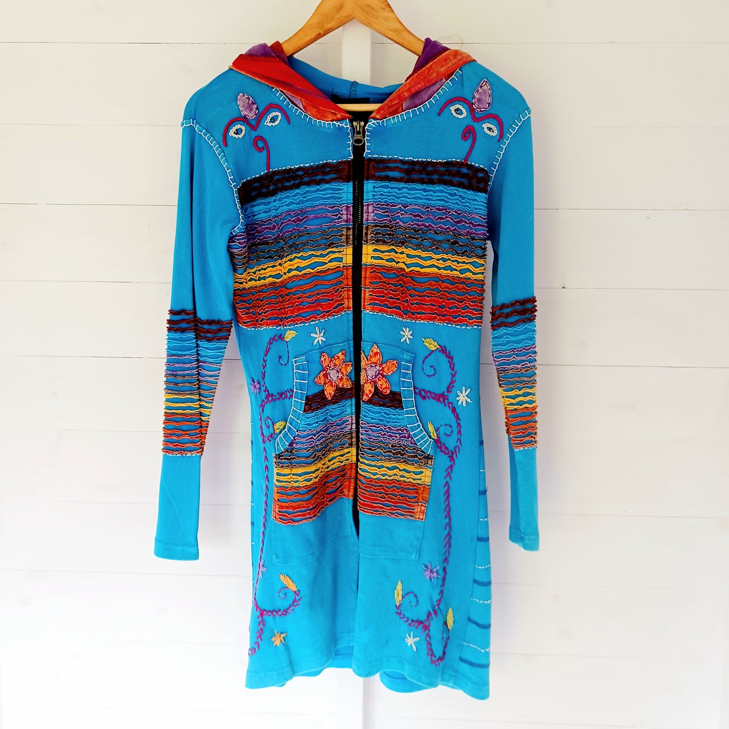 Make a bold statement with this handmade turquoise Pixie Jacket, a striking patchwork coat designed for free spirits and lovers of expressive, bohemian fashion. Crafted in Nepal from soft, stretchy cotton jersey, this longline jacket blends vibrant colours, artistic prints, and intricate detailing into a truly unique outerwear piece.