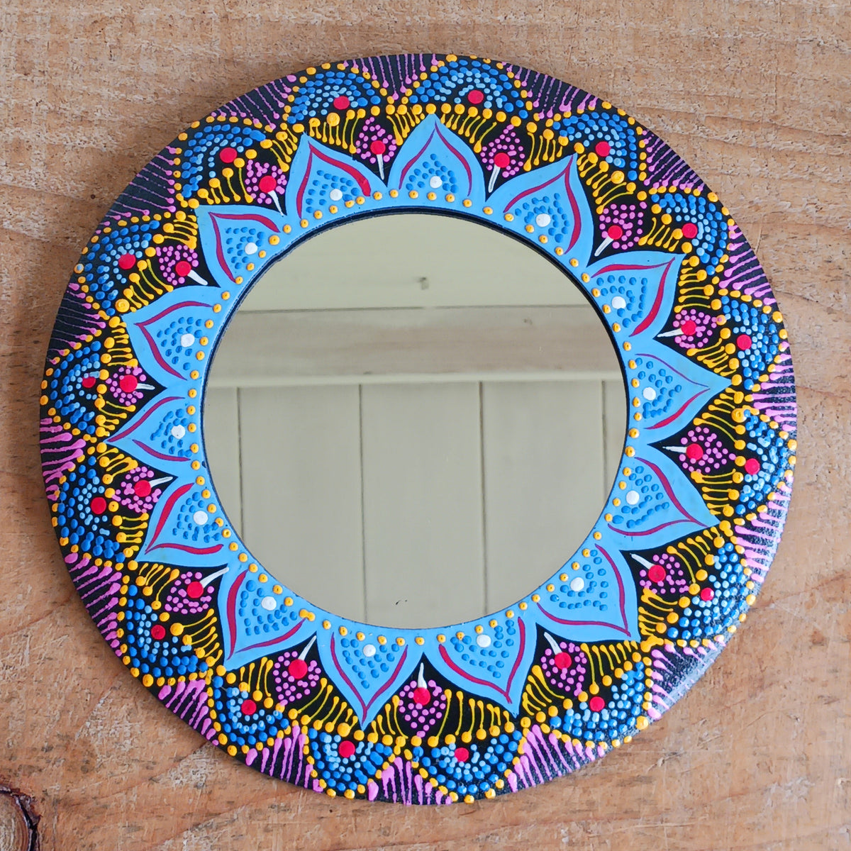 Add a splash of colour and bohemian charm to your home with this beautiful Dot Painted Mirror, handcrafted in Bali by skilled artisans. Featuring a wooden frame decorated with intricate dot painting, its vibrant colours and mandala-inspired patterns create a striking decorative piece that combines everyday practicality with artistic style.