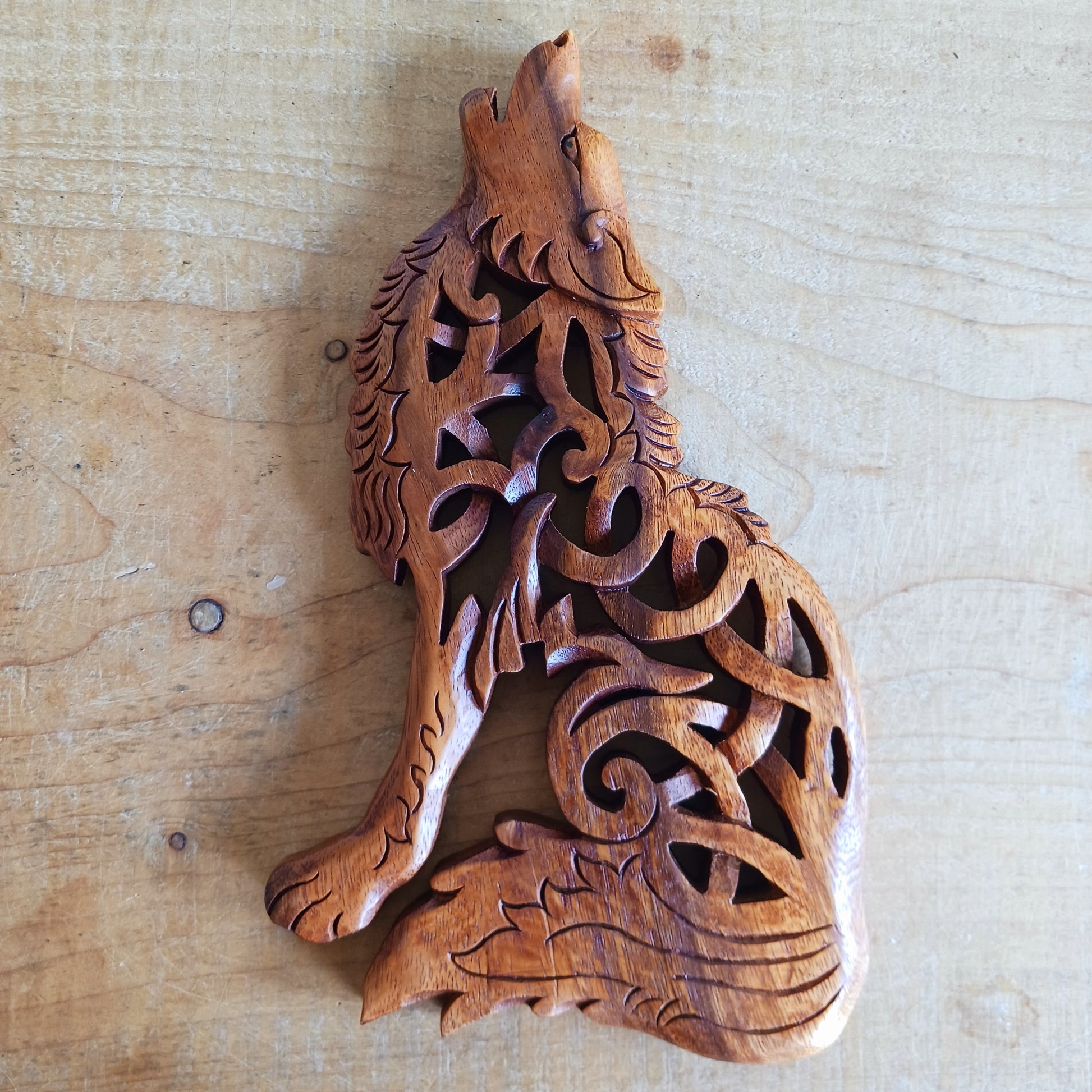 Bring the spirit of the wild into your home with this beautiful and striking Howling Wolf Celtic Knotwork Wooden Plaque. Hand-carved by skilled artisans in Bali, this open-work wooden wall plaque features an upright wolf with its head thrown back in a powerful howl.