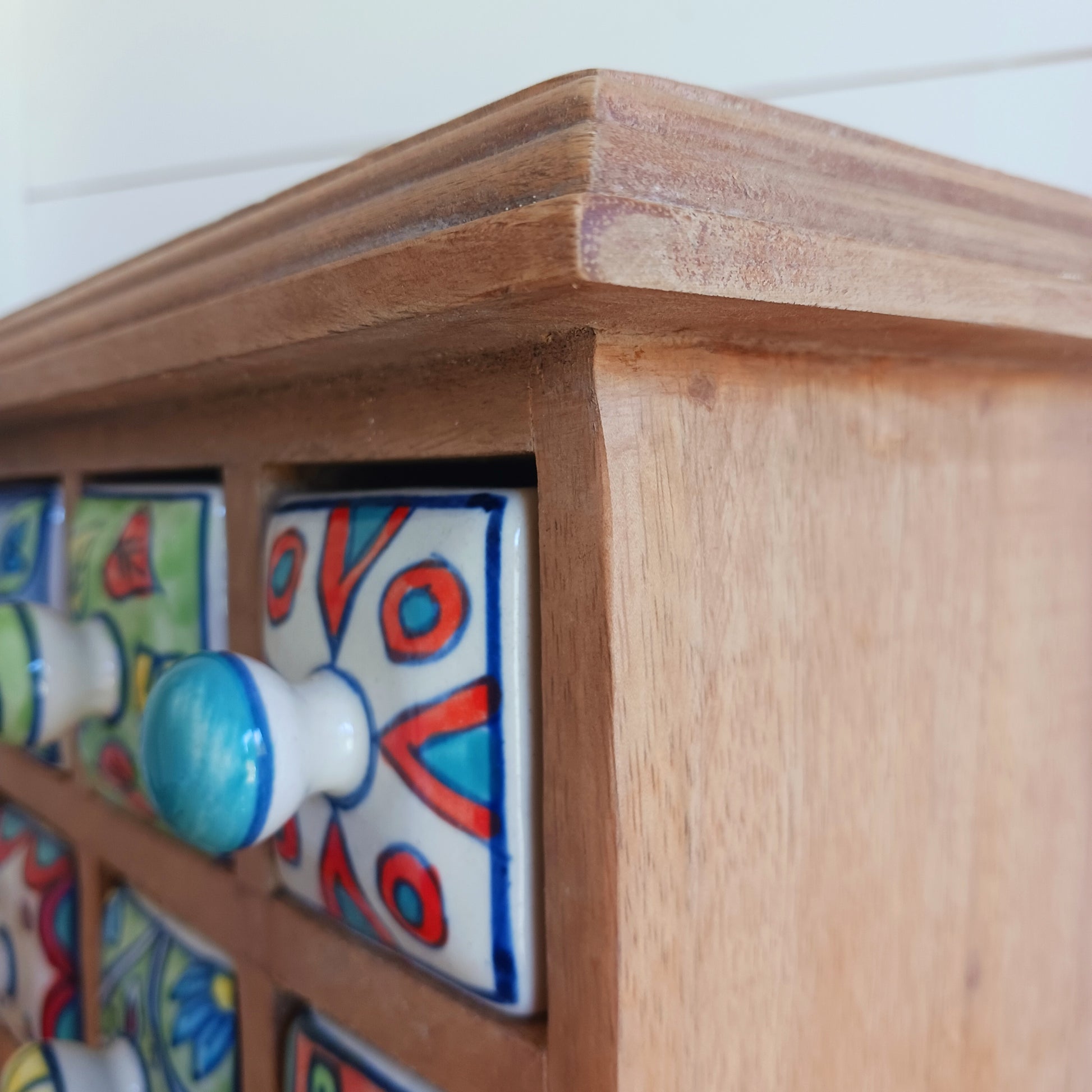 Add a touch of authentic Indian craftsmanship to your home with this Handcrafted Indian Ceramic 16-Drawer Mini Chest. Featuring 16 individually hand-painted ceramic drawers set within a warm wooden frame, this decorative storage cabinet is both practical and beautifully unique.
