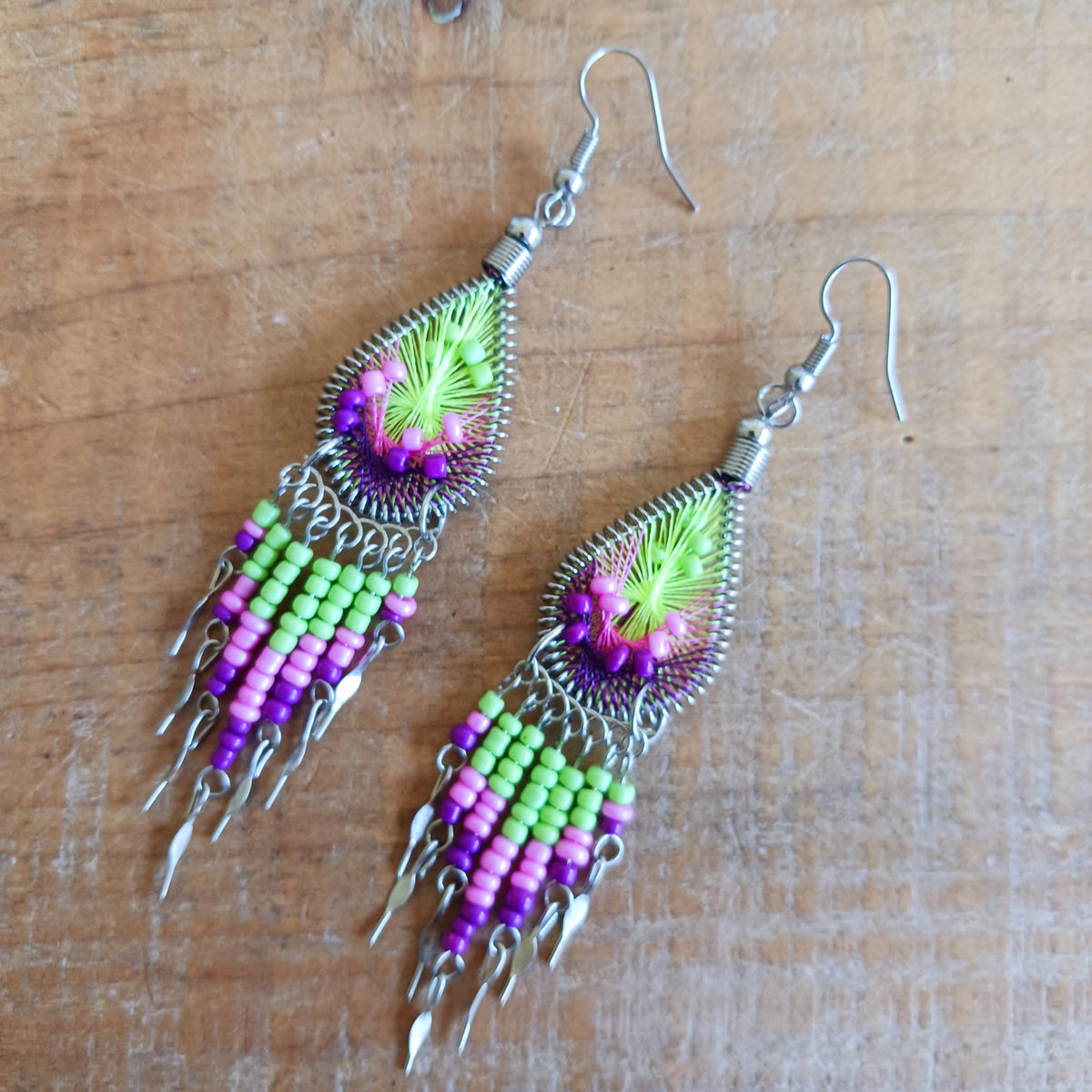 Add a splash of colour to your look with these beautiful handmade Peruvian woven teardrop earrings. Inspired by the vibrant colours and patterns of a peacock feather, each earring features intricate woven detailing complemented by coordinating beads and delicate silver-tone embellishments.
