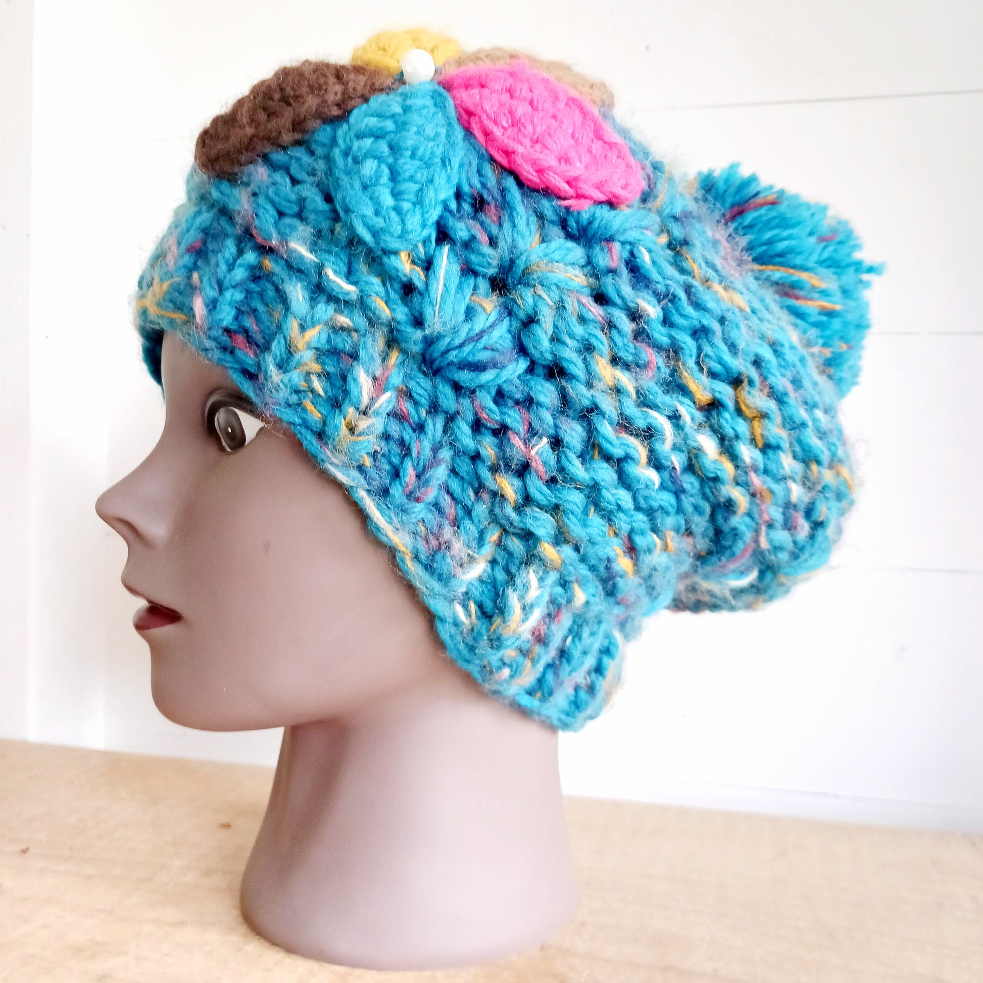 Stay warm in style with this charming knitted wool flower bobble hat, designed to bring both comfort and personality to your winter wardrobe. Crafted from soft, insulating wool, this cozy beanie keeps you snug even on the coldest days.