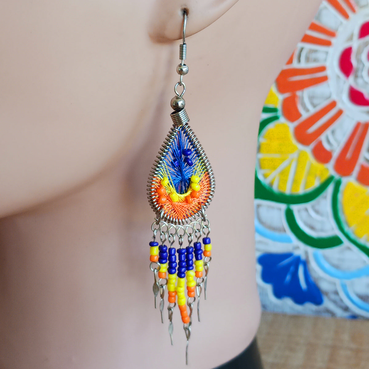 Add a splash of colour to your look with these beautiful handmade Peruvian woven teardrop earrings. Inspired by the vibrant colours and patterns of a peacock feather, each earring features intricate woven detailing complemented by coordinating beads and delicate silver-tone embellishments.
