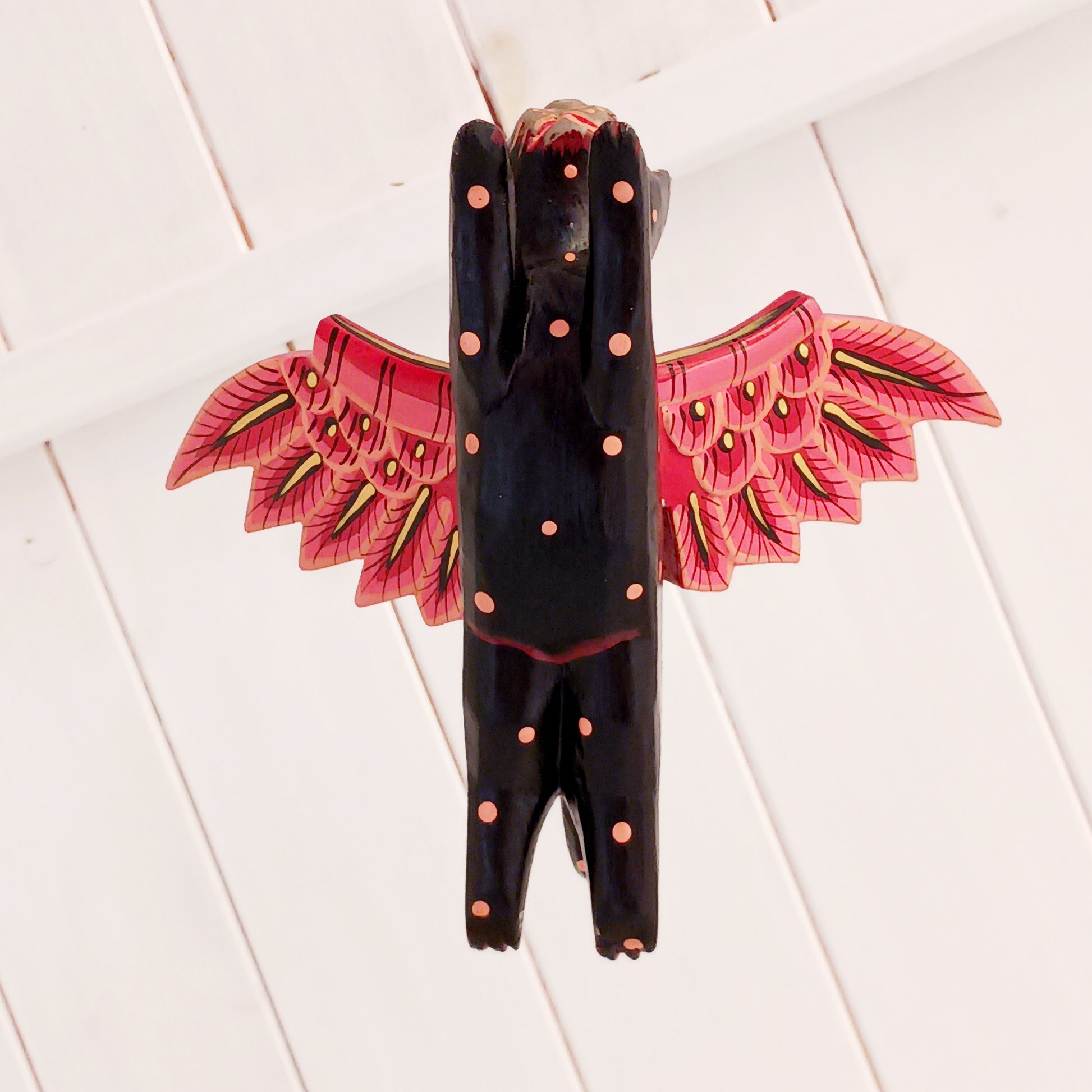 Bring a touch of mystery and magical drama to your home with this striking flying cat mobile, hand carved and painted by skilled artisans in Bali. Featuring a deep black cat with vivid red wings and intricate painted detailing, this unusual hanging decoration makes a bold statement wherever it is displayed.