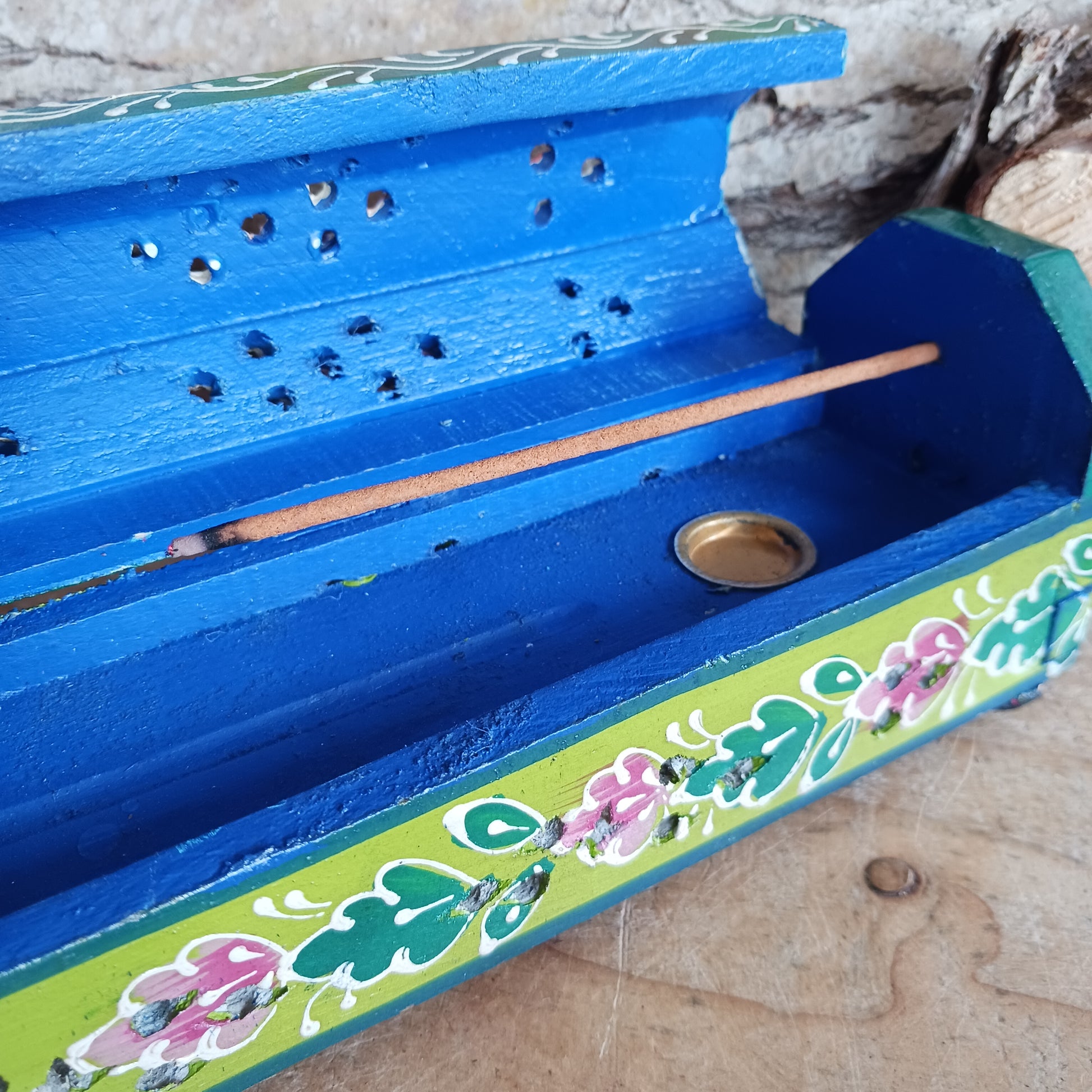 This beautiful pink and green wooden Incense box has been hand painted and has a curved hinged lid. It can accommodate both incense sticks and cones. There is also a place for you to safely store your incense sticks at the bottom on the box.