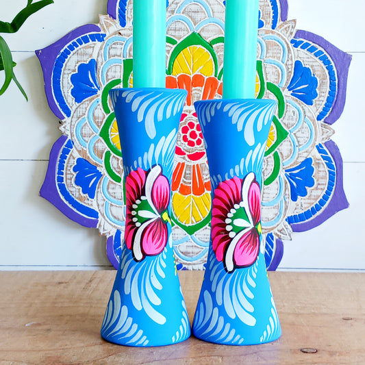Hand painted in a vibrant blue hue and adorned with the Shapla (waterlily) flower — the national flower of Bangladesh, this fair trade candle holder is a true statement piece. Display it prominently or gift it to someone special as a unique, ethical, and meaningful present. Beautiful on its own or paired with others, it adds warmth, tradition, and cheerful design to any space.