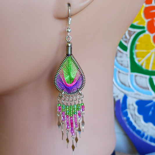 These beautiful and eye-catching earrings are handmade in Peru and feature an array of gorgeous colours. A woven teardrop, similar in style to a peacock feather, is finished with co-ordinating beads and silver embellishments. Ideal for a night out or for dressing up your boho look!