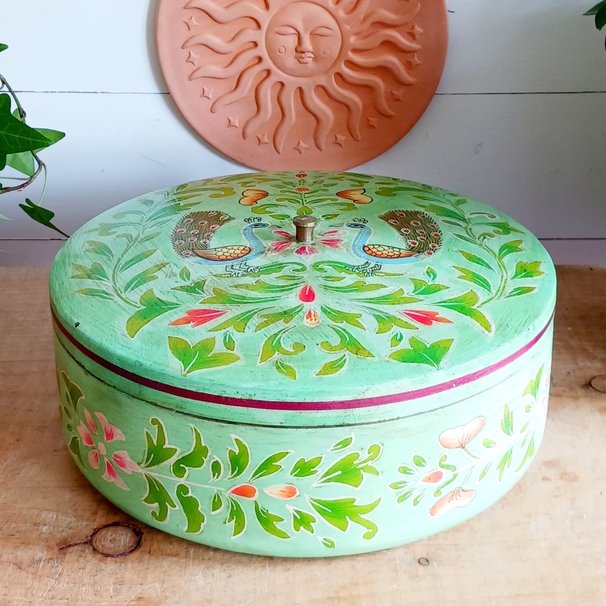 Bring a touch of traditional Indian craftsmanship to your home with this beautiful Handmade Indian Wooden Peacock Decorative Box. Expertly crafted from wood and hand-painted by skilled artisans, this charming round storage box features an elegant peacock design on the pull-off lid, symbolizing beauty, grace, and prosperity.