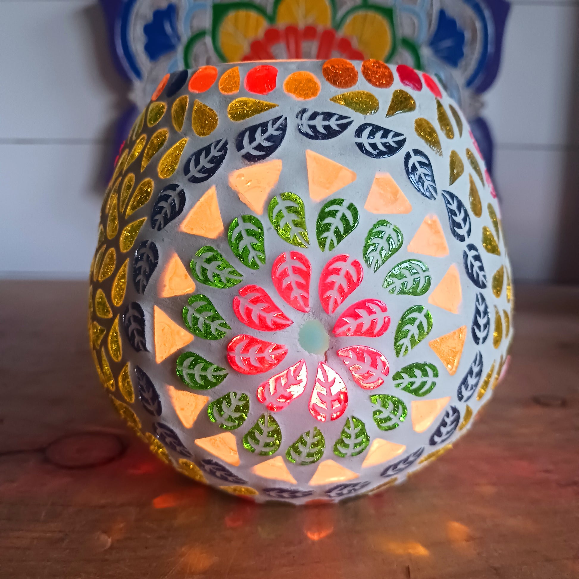 These beautiful tealight holders are a mosaic mixture of pearlescent and block colours that create a vibrant floral mandala design on this glass tealight holder. Pop in a lit tealight to warm the atmosphere with multi colour vibes on outdoor summer evenings, or indoors to brighten the long dark evenings.