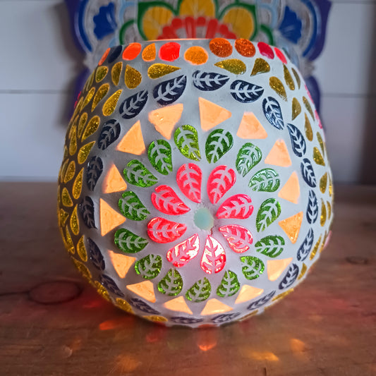 These beautiful tealight holders are a mosaic mixture of pearlescent and block colours that create a vibrant floral mandala design on this glass tealight holder. Pop in a lit tealight to warm the atmosphere with multi colour vibes on outdoor summer evenings, or indoors to brighten the long dark evenings.