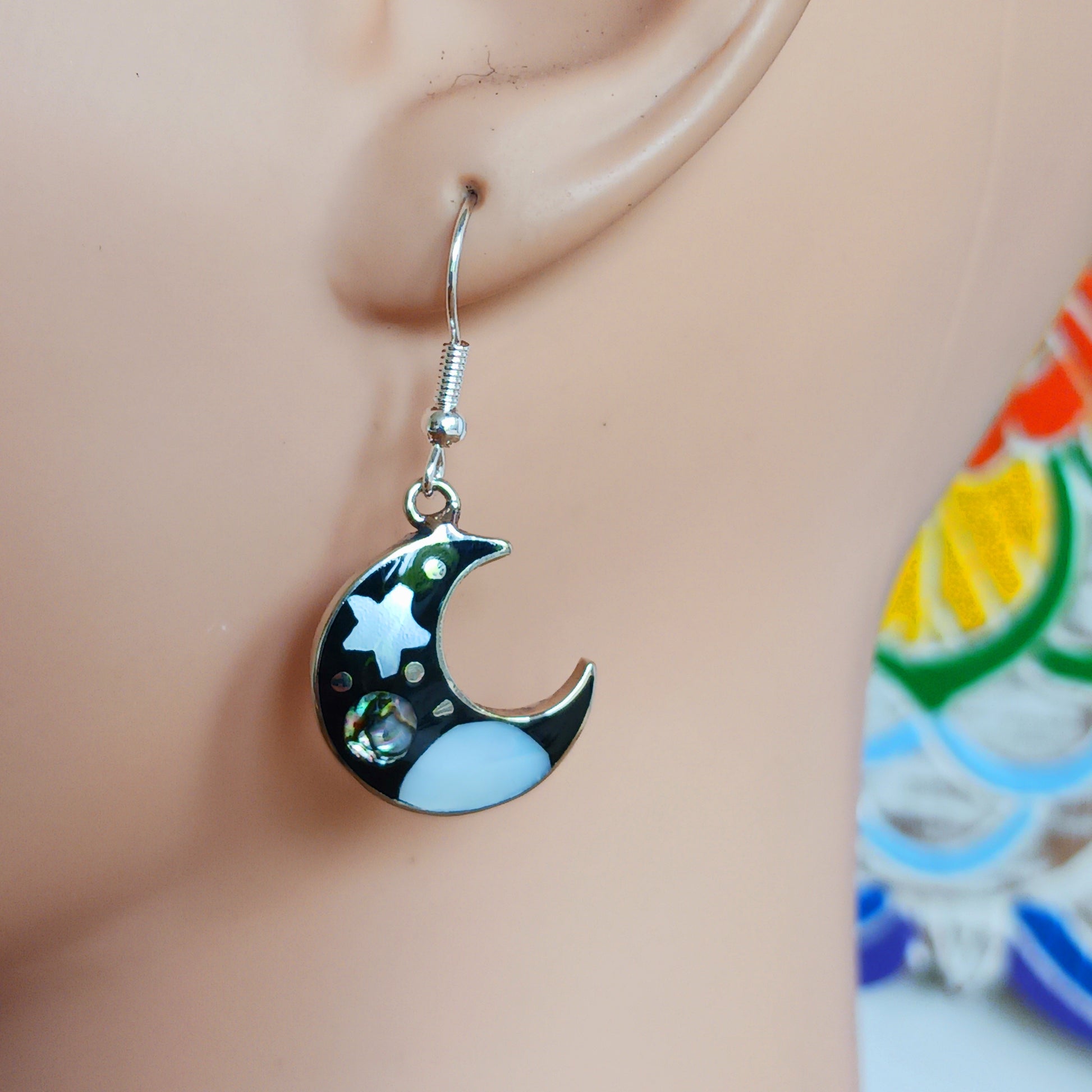This set of beautiful celestial themed earrings are hand crafted in Taxco, Mexico. Utilising a eye-catching crescent moon design created using traditional Alpaca steel as the frame. These earrings have a celestial theme created using dyed, iridescent abalone shell.