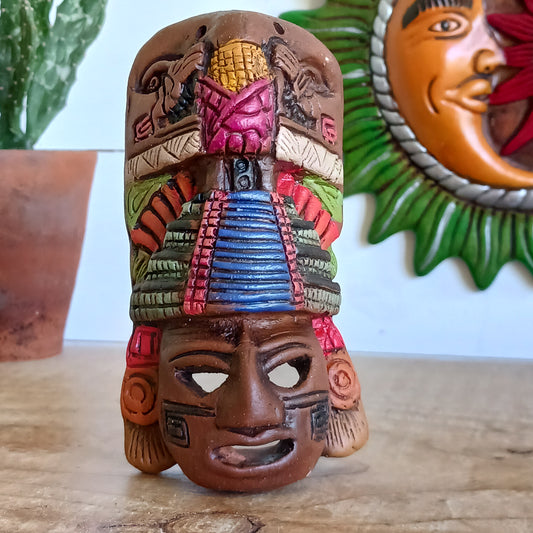 This little, handcrafted ceramic mask depicts a Mayan god, decorated with a pyramid headdress. The famous pyramids of Chichén Itzá in Mexico include El Castillo, a pyramid dedicated to Kukulcan, a Mayan serpent god. They are a major attraction at the archaeological site, recognized as one of the new Seven Wonders of the World. The pyramid was built by the Mayan civilization between the 9th and 12th centuries CE.