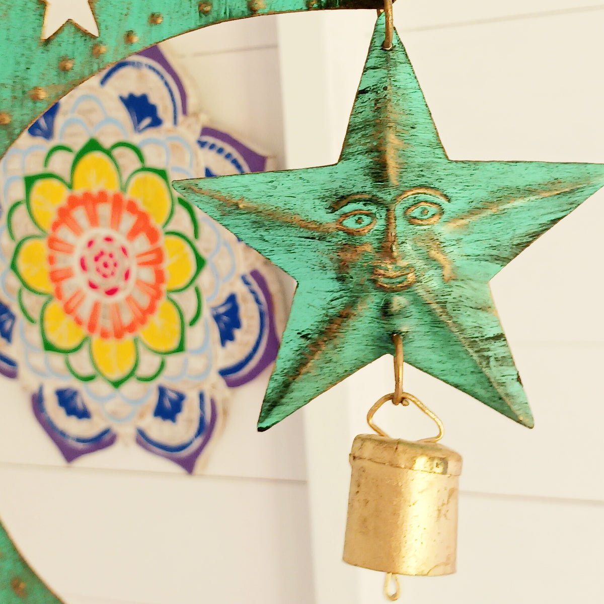 Bring a touch of celestial charm to your home with this rustic crescent moon wind chime, beautifully finished in an aged verdigris green. Handmade by skilled artisans in India, this decorative iron wall hanging features pierced star detailing, a hanging star charm and traditional Indian brass bells.