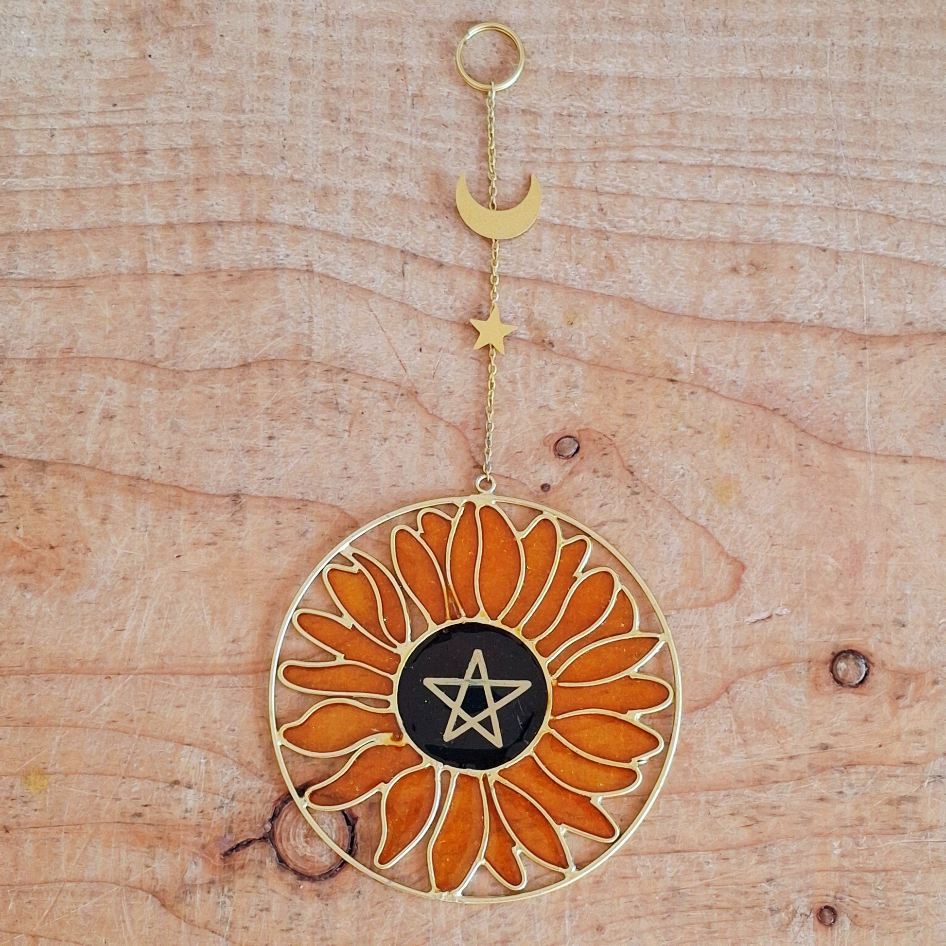 Add a touch of sunshine to the home with this Summer Solstice sunflower suncatcher. This charming suncatcher is inspired by the Summer Solstice, featuring a beautifully detailed sunflower, pentagram, star and crescent moon design made from metal and resin. Hang it in the window to catch the light and bring a cheerful, colourful glow to any room.