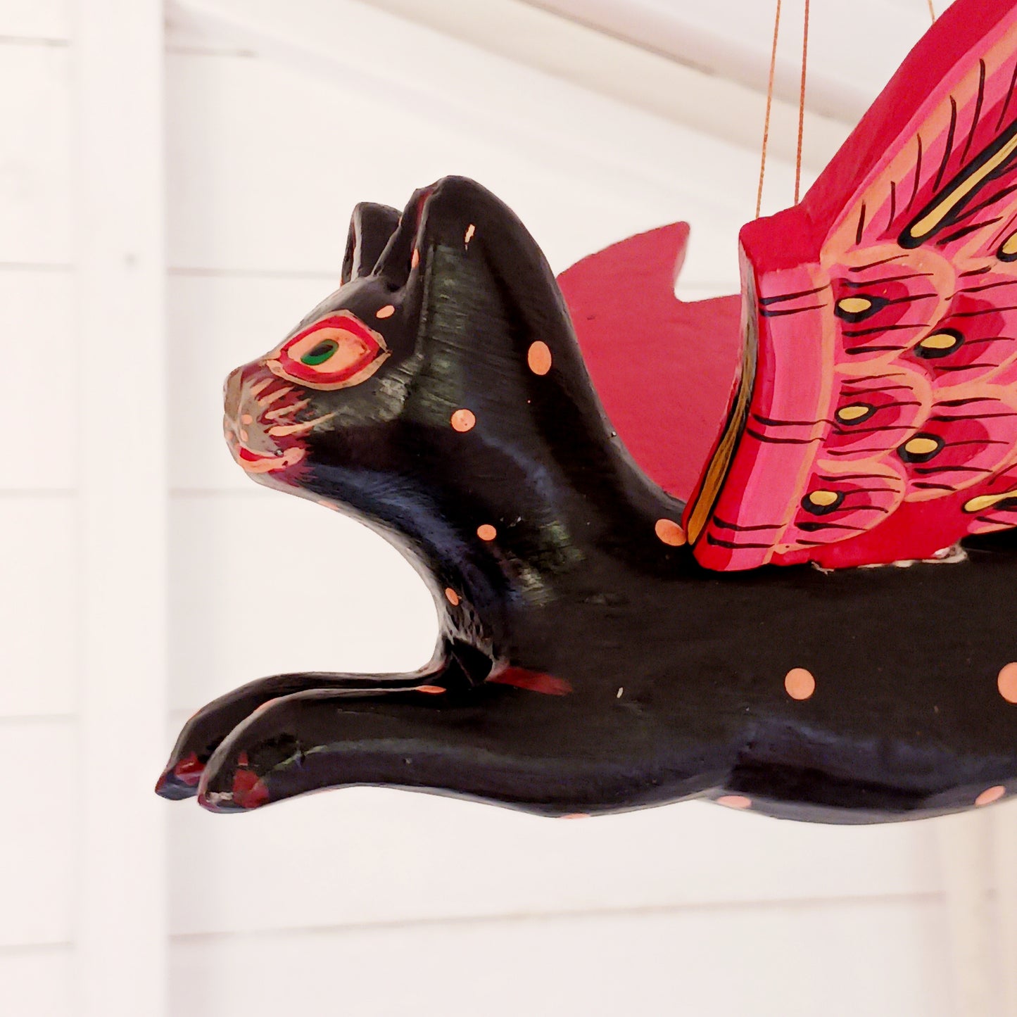 Bring a touch of mystery and magical drama to your home with this striking flying cat mobile, hand carved and painted by skilled artisans in Bali. Featuring a deep black cat with vivid red wings and intricate painted detailing, this unusual hanging decoration makes a bold statement wherever it is displayed.
