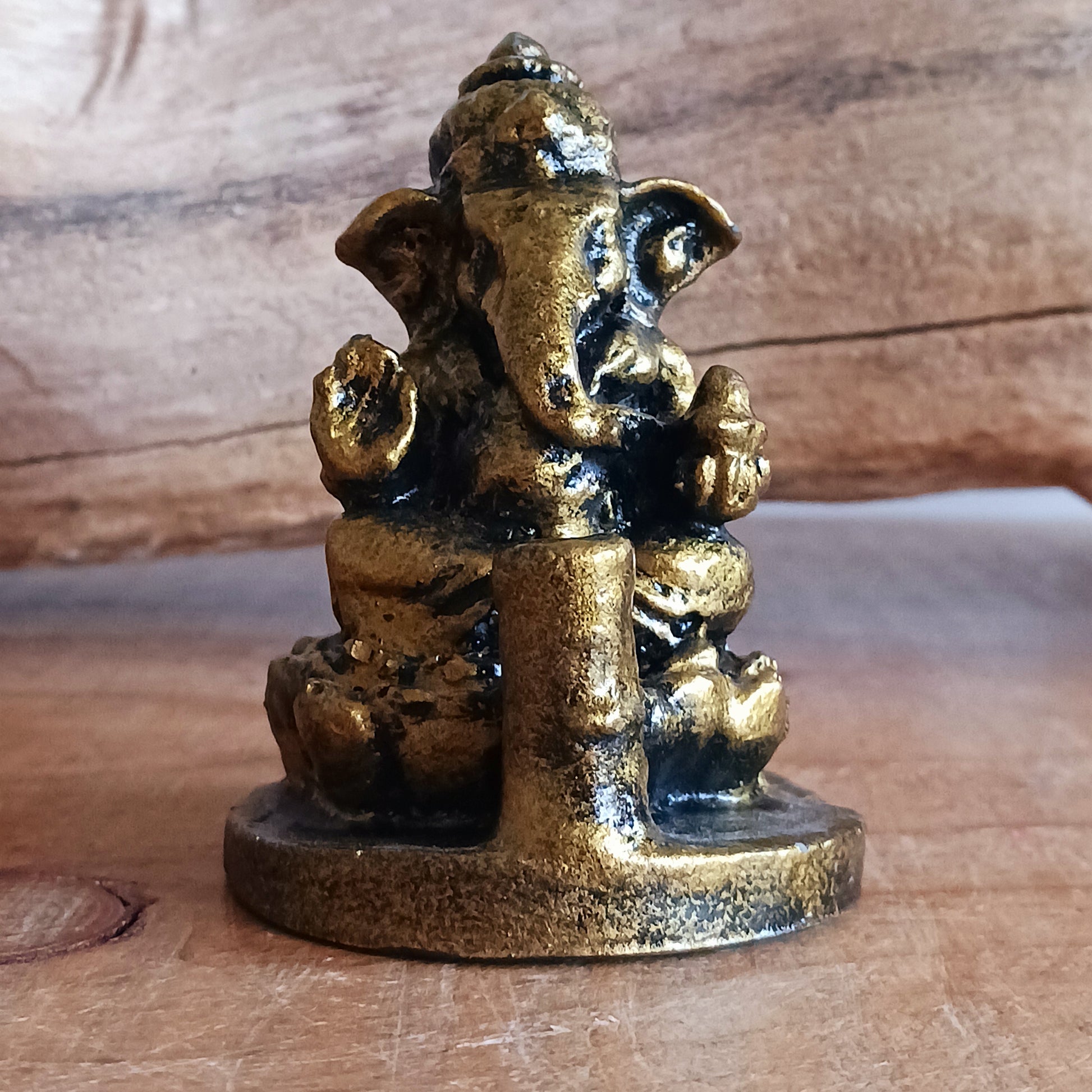 A small resin casting of Ganesh in a golden antique-style finish that also serves as an incense holder.