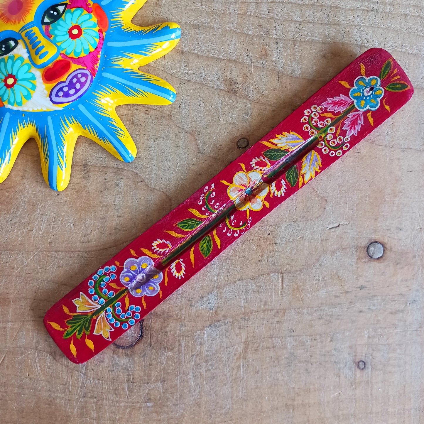 Add a touch of traditional craftsmanship to your home with this hand-painted red wooden incense stick holder, beautifully decorated with intricate floral designs. Carefully sourced Fairtrade from India, each holder reflects authentic artisan work and cultural artistry.