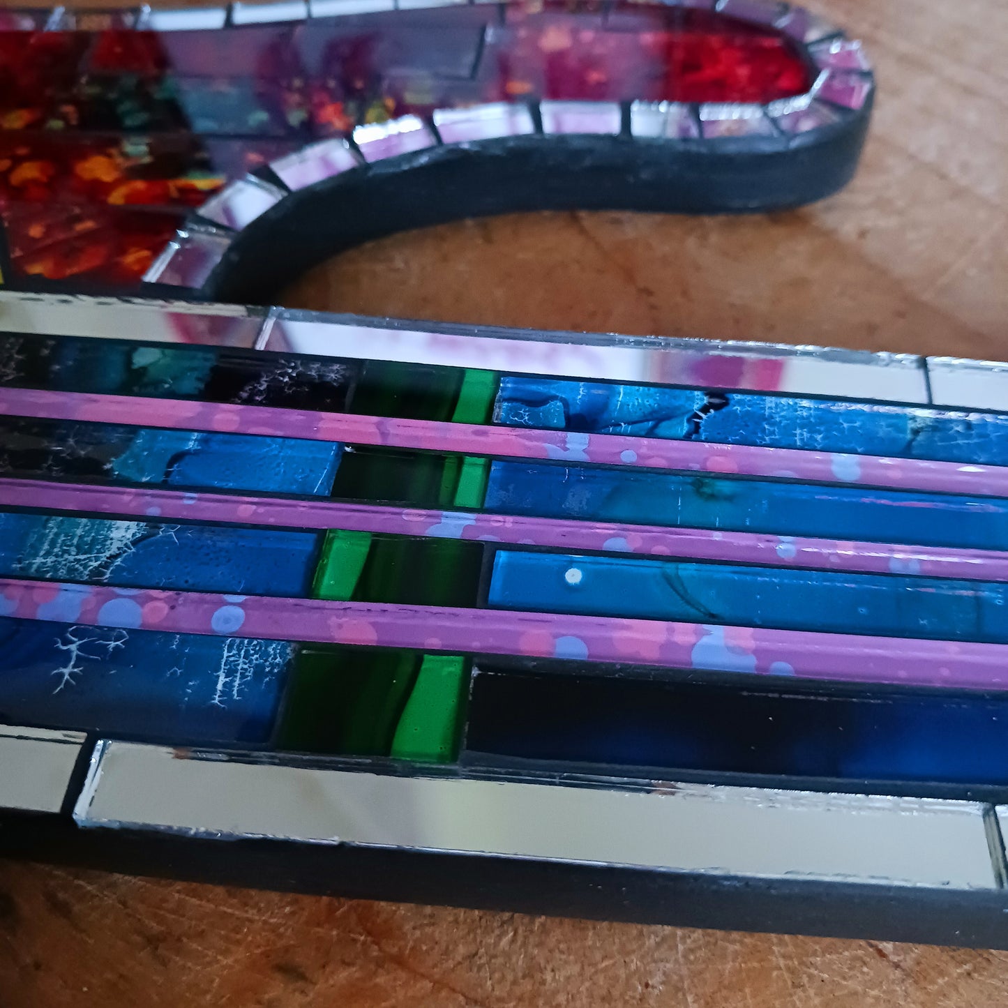 Handcrafted from shimmering, individually placed glass tiles, this stunning guitar-shaped glass mosaic mirror blends creativity, rhythm, and craftsmanship into one striking wall décor accent.