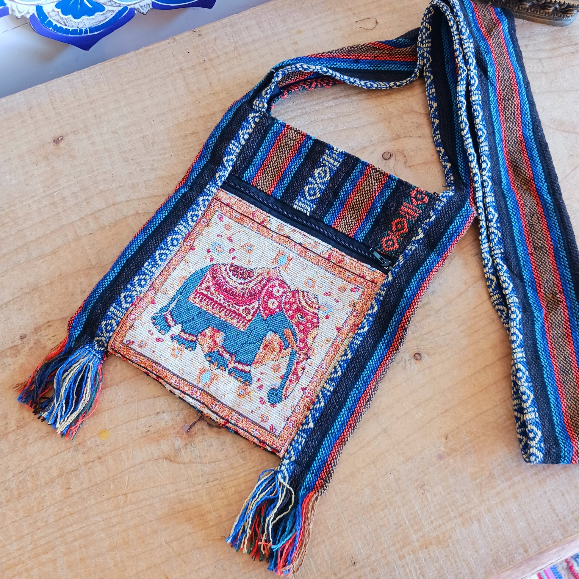 his handy little shoulder bag has a wide strap that is long enough to use as a shoulder or crossbody bag and also makes it comfortable to wear for long periods. The main fabric is traditional with a beautiful embroidered elephant design on the front. The bag is finished with tassels.