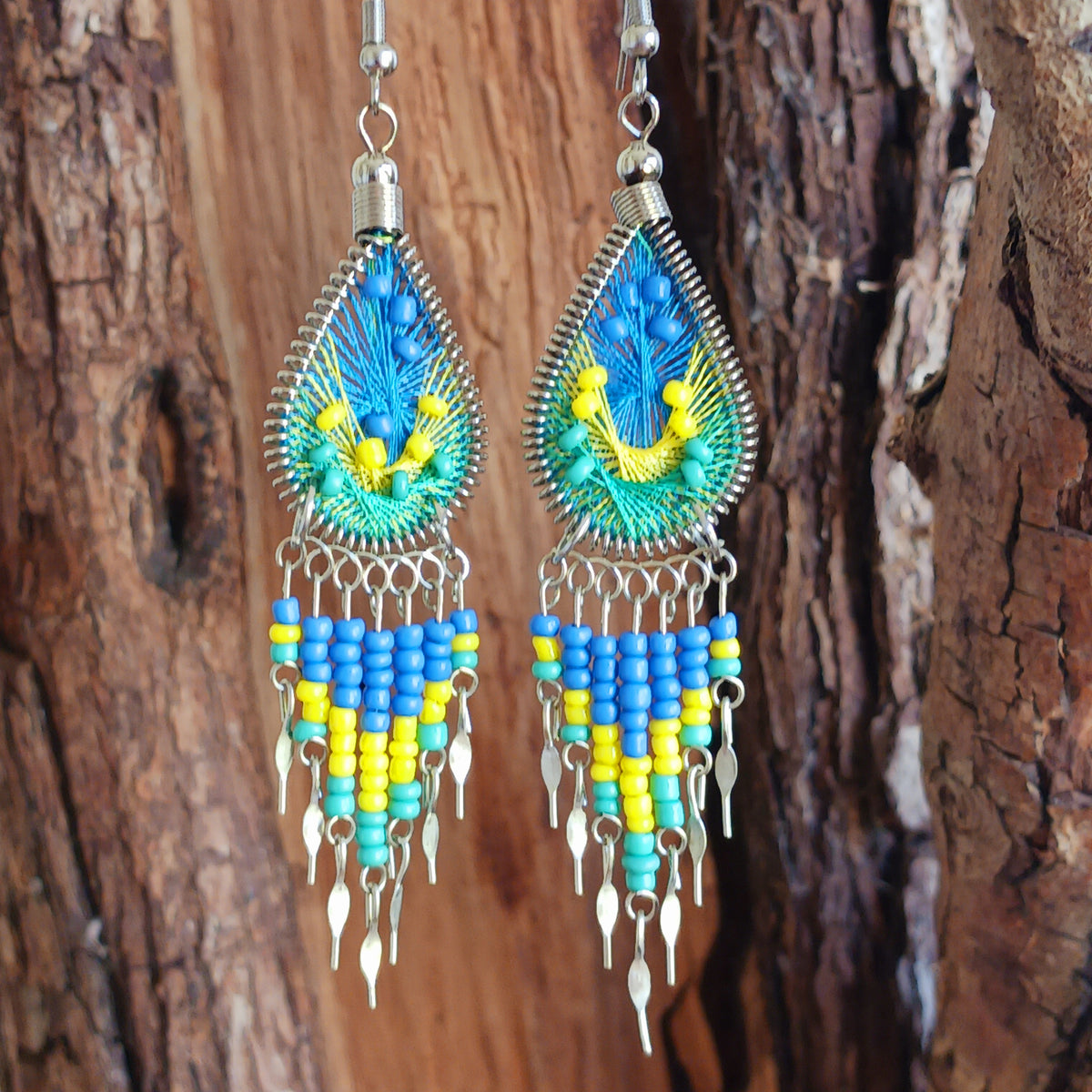 Add a splash of colour to your look with these beautiful handmade Peruvian woven teardrop earrings. Inspired by the vibrant colours and patterns of a peacock feather, each earring features intricate woven detailing complemented by coordinating beads and delicate silver-tone embellishments.