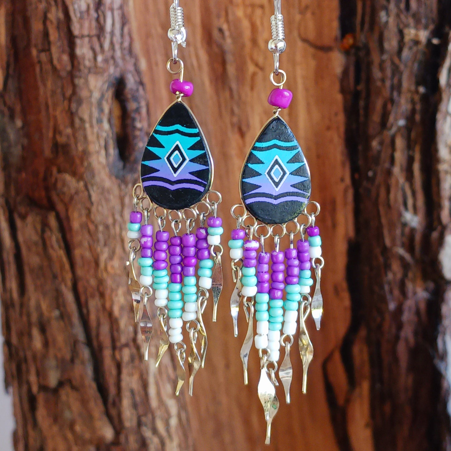 These beautiful and eye-catching earrings are handmade in Peru and feature traditional Incan patterns on the front, the back is coloured black. They are shaped in a teardrop style and are finished with coloured coordinating beads, silver embellishments and silver-plated hooks.