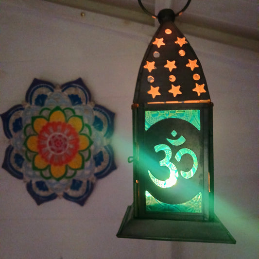 Bring warmth, colour and spiritual harmony to your home with this beautiful Om Symbol Glass Lantern. Designed with vibrant coloured glass panels and a decorative metal cut-out canopy, this lantern creates a calming glow that enhances meditation spaces, yoga rooms and home décor.
