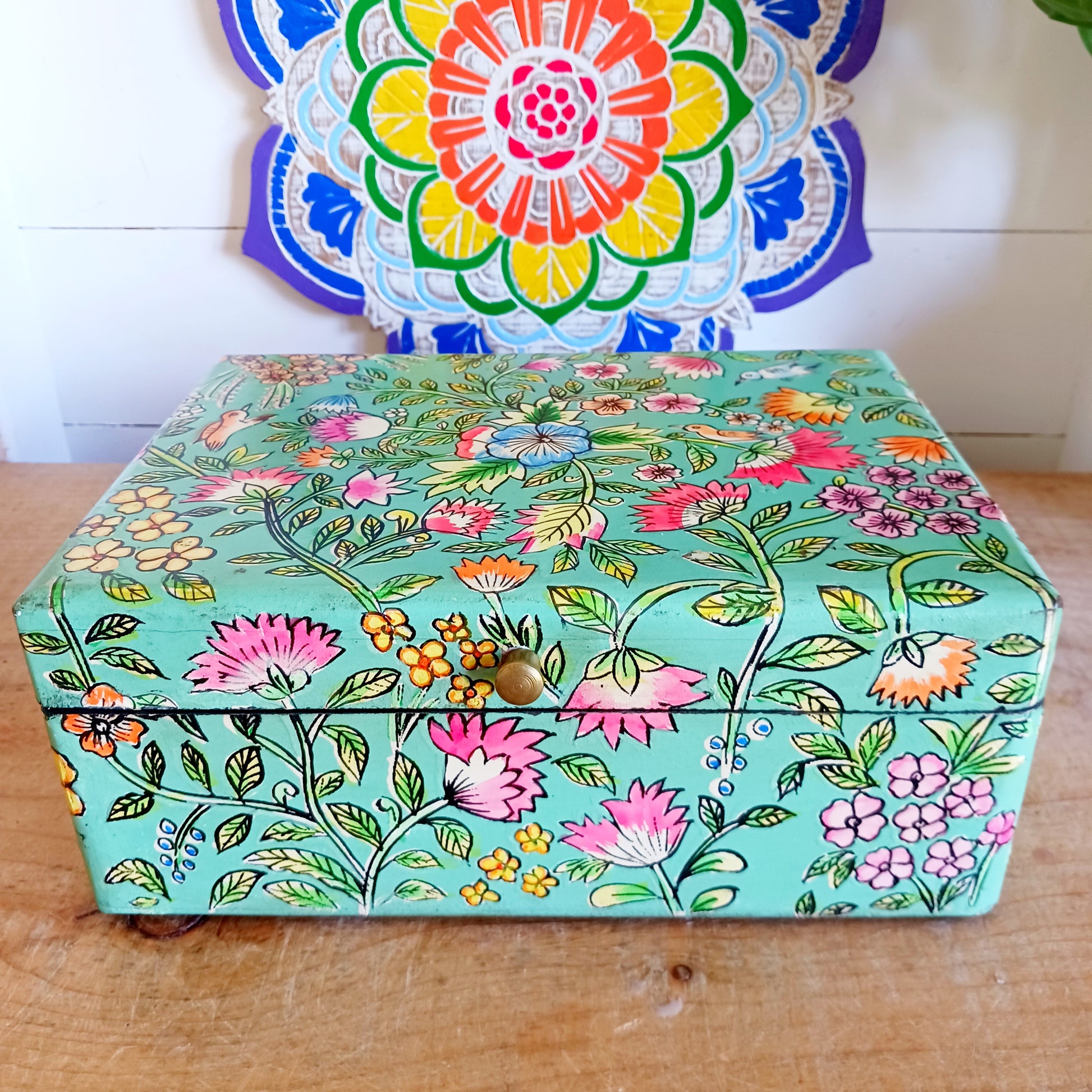 The Saanvi Handcrafted Large Wooden Box is a sustainable gift of beauty, designed to bring charm and practicality to any space. Expertly hand-painted in a bright mixed floral pattern on a pale blue background, this decorative box exudes artisanal elegance. The hinged lid is accented with a small gold-colored knob for a refined touch, while the deep midnight interior offers ample storage for trinkets, jewellery, and cherished keepsakes.