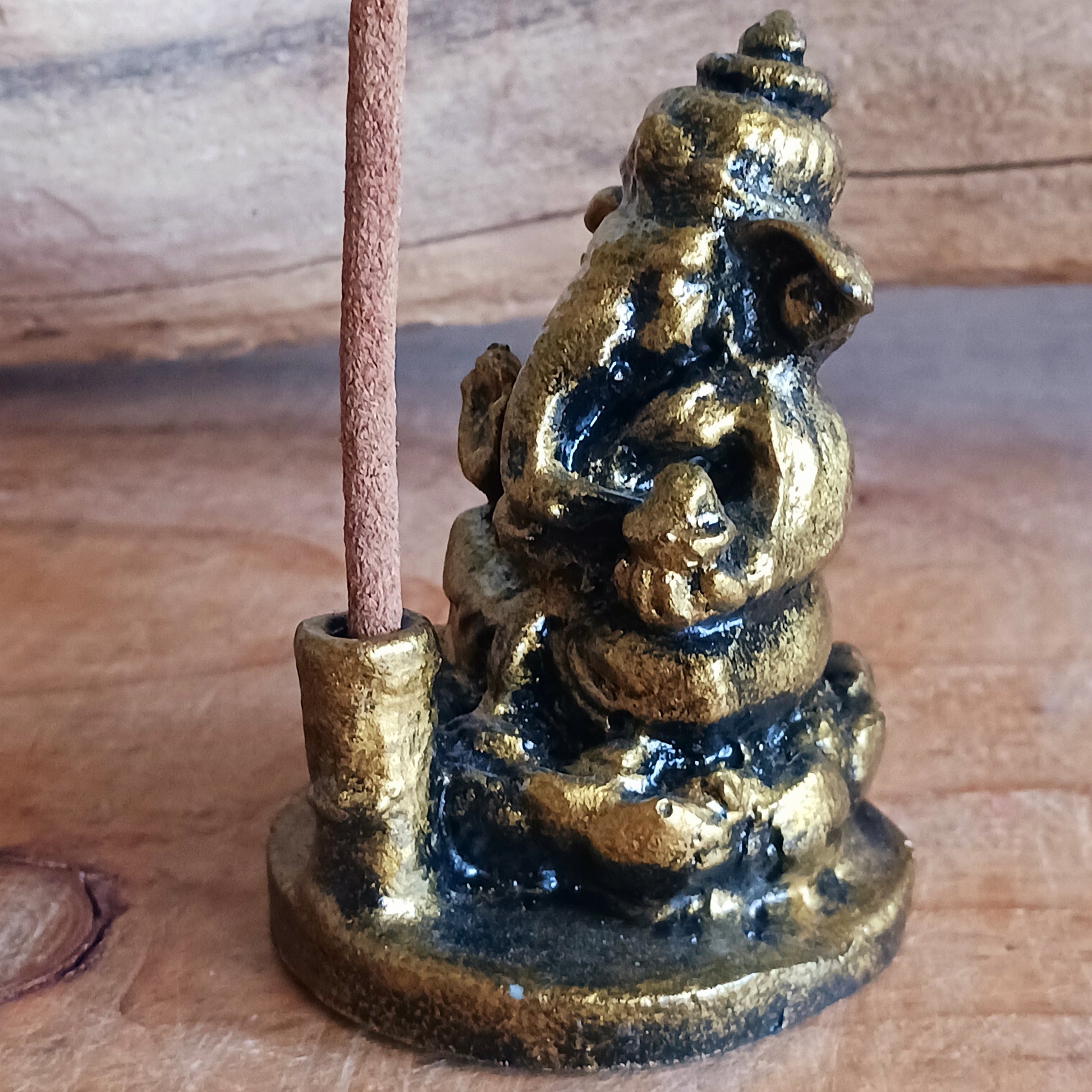 A small resin casting of Ganesh in a golden antique-style finish that also serves as an incense holder.