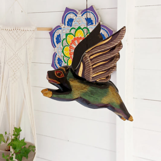 Invite protective energy and traditional charm into your home with this handcrafted Flying Pig Spirit Guardian from Bali. Known locally as a "Cradle Guardian," this winged figure is believed to ward off negative entities and is often placed in temples or homes, suspended from elevated areas like doorways or windows. Its downward-facing posture channels protection, while the strong twine loop allows for easy hanging. 