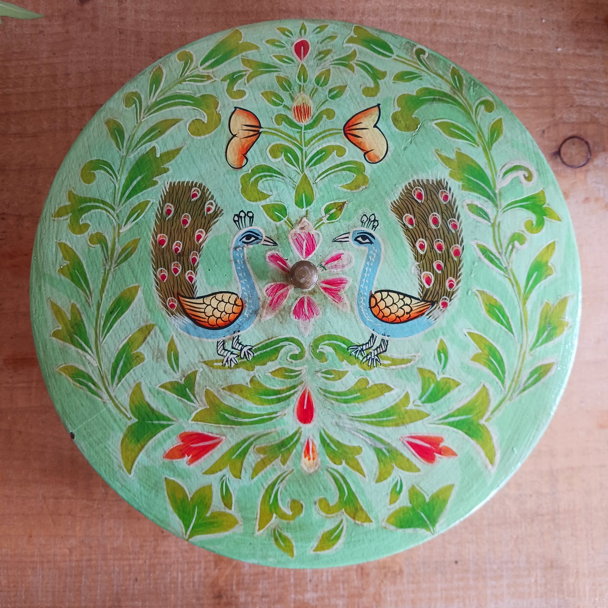 Bring a touch of traditional Indian craftsmanship to your home with this beautiful Handmade Indian Wooden Peacock Decorative Box. Expertly crafted from wood and hand-painted by skilled artisans, this charming round storage box features an elegant peacock design on the pull-off lid, symbolizing beauty, grace, and prosperity.