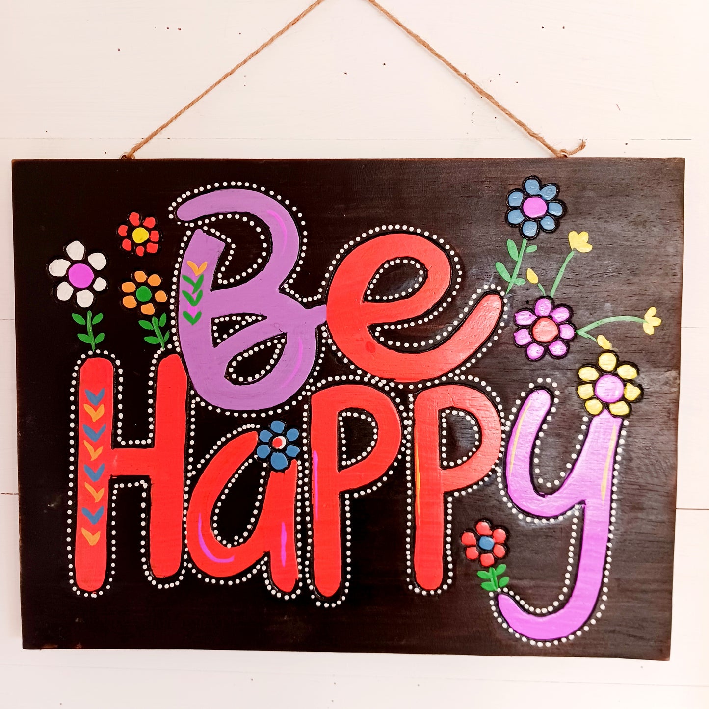Bring joy and positivity into your home with this handmade “Be Happy” Wall Plaque. Expertly crafted and finished by skilled artisans in Indonesia, this vibrant piece features a bold floral design surrounding the uplifting words “Be Happy.” Each plaque is unique, reflecting the natural textures and craftsmanship of traditional artistry.