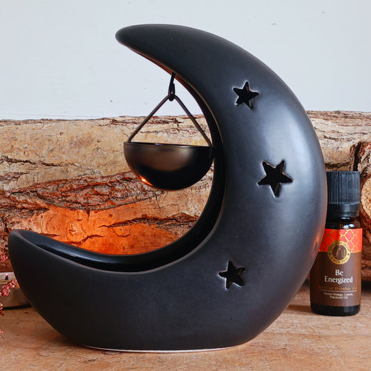 Bring a touch of midnight magic to your home with this black crescent moon oil burner, a beautifully designed piece that blends home fragrance with celestial décor. Featuring delicate star cut-outs, this oil burner casts a soft, glowing light while gently filling your space with the scent of your favourite fragrance or essential oils.