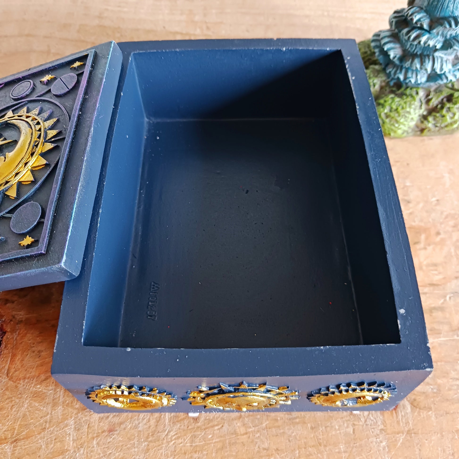 This unusual decorated resin box has raised astrology symbols and a detailed sun and moon design with a gold finish. 
 This celestial style is perfect for holding trinkets, crystals and other small objects for safe keeping.