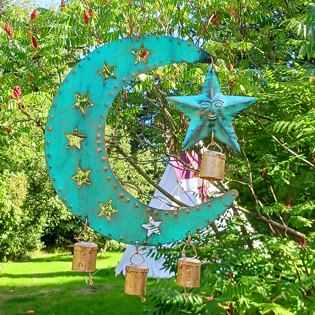 Bring a touch of celestial charm to your home with this rustic crescent moon wind chime, beautifully finished in an aged verdigris green. Handmade by skilled artisans in India, this decorative iron wall hanging features pierced star detailing, a hanging star charm and traditional Indian brass bells.