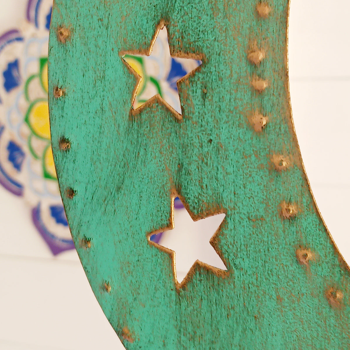 Bring a touch of celestial charm to your home with this rustic crescent moon wind chime, beautifully finished in an aged verdigris green. Handmade by skilled artisans in India, this decorative iron wall hanging features pierced star detailing, a hanging star charm and traditional Indian brass bells.