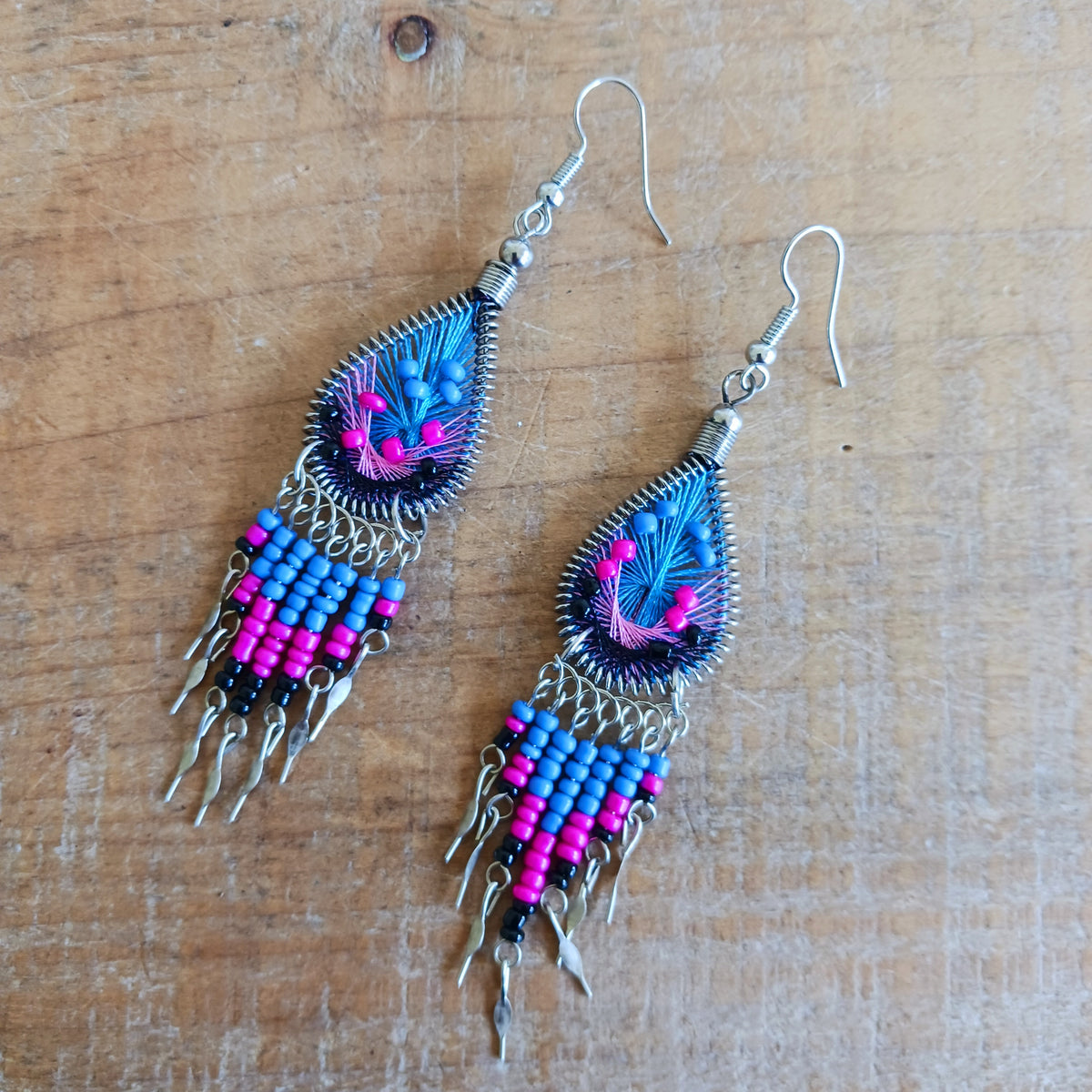 Add a splash of colour to your look with these beautiful handmade Peruvian woven teardrop earrings. Inspired by the vibrant colours and patterns of a peacock feather, each earring features intricate woven detailing complemented by coordinating beads and delicate silver-tone embellishments.