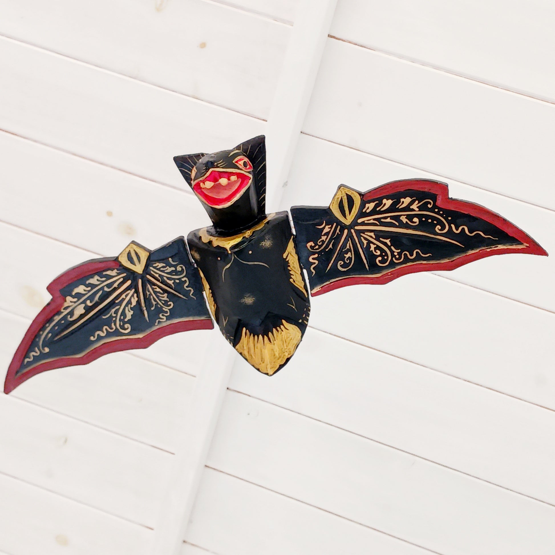 Bring a touch of gothic magic into your home with this striking hand-carved wooden flying bat mobile, handmade by skilled artisans in Bali, Indonesia. With its wings dramatically outstretched to approximately 50cm wide, this unusual hanging decoration makes a bold statement suspended from a ceiling, doorway, window or display area.