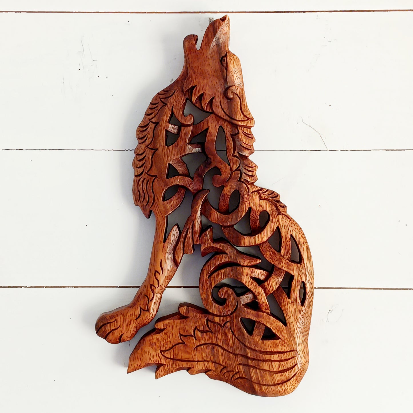 Bring the spirit of the wild into your home with this beautiful and striking Howling Wolf Celtic Knotwork Wooden Plaque. Hand-carved by skilled artisans in Bali, this open-work wooden wall plaque features an upright wolf with its head thrown back in a powerful howl.