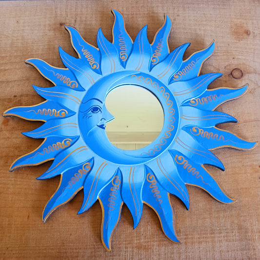 Elevate your home with the mystical charm of our Sun &amp; Moon Mirror. Lovingly handmade by fairtrade artisans, this unique piece features a beautifully painted sun and moon design in vibrant blue tones. Perfect for adding a touch of spirituality, harmony, and positive energy to your living space, this mirror doubles as both a functional piece and captivating art. Ideal for bedrooms, meditation spaces, or as a thoughtful gift for someone special.