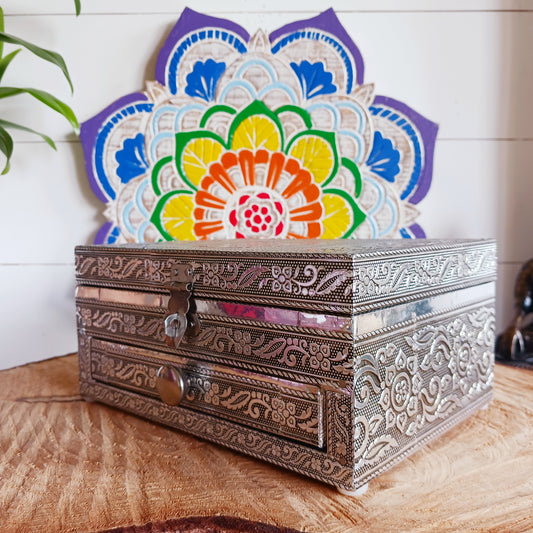 This beautiful silver colour embossed aluminium jewellery box has plenty of space for you to keep you jewellery and other valueables, and comes with a pull-out drawer.  It is lined with black cotton velvet and intricately decorated with a hamsa hand on the lid, and ornate bordering.
