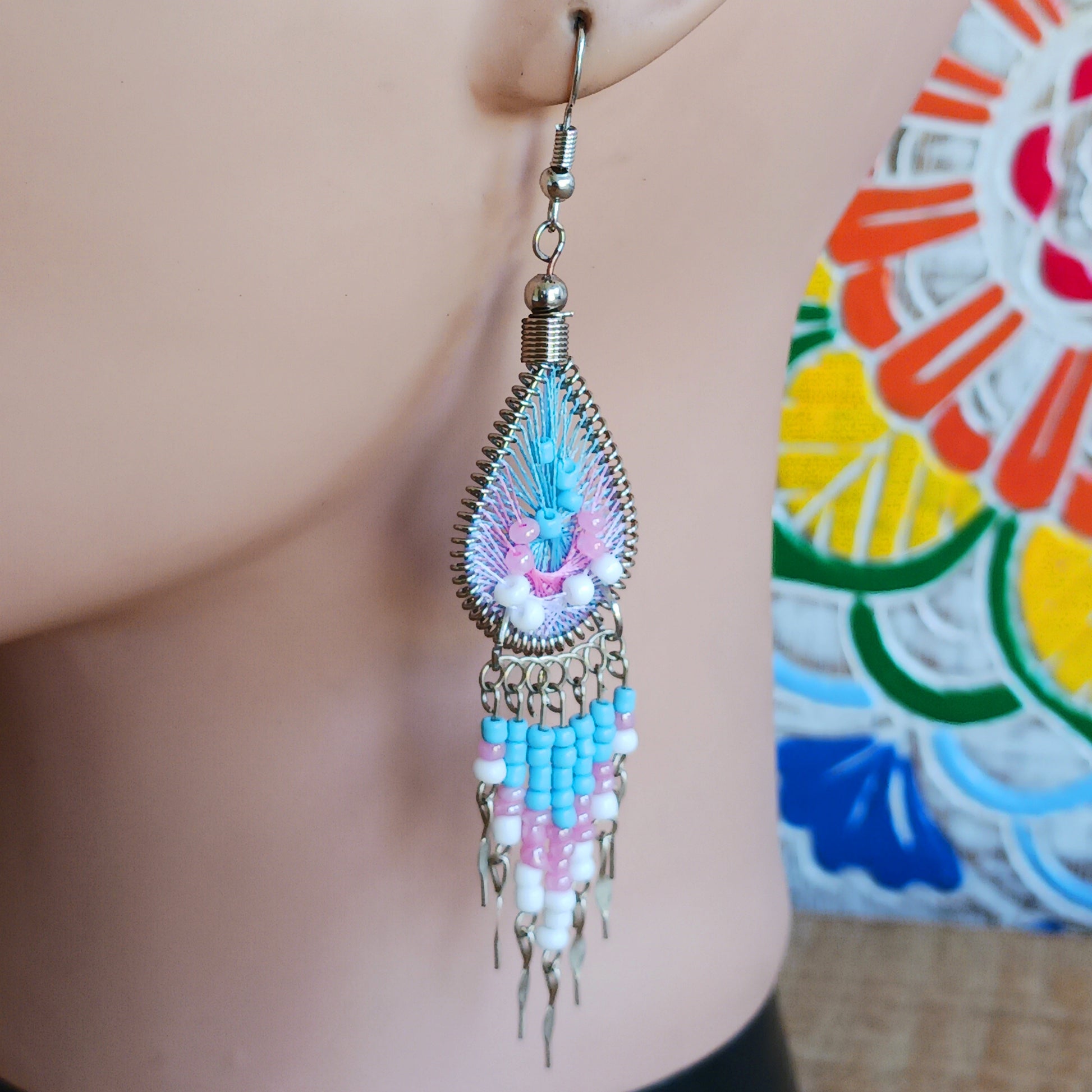 Add a splash of colour to your look with these beautiful handmade Peruvian woven teardrop earrings. Inspired by the vibrant colours and patterns of a peacock feather, each earring features intricate woven detailing complemented by coordinating beads and delicate silver-tone embellishments.