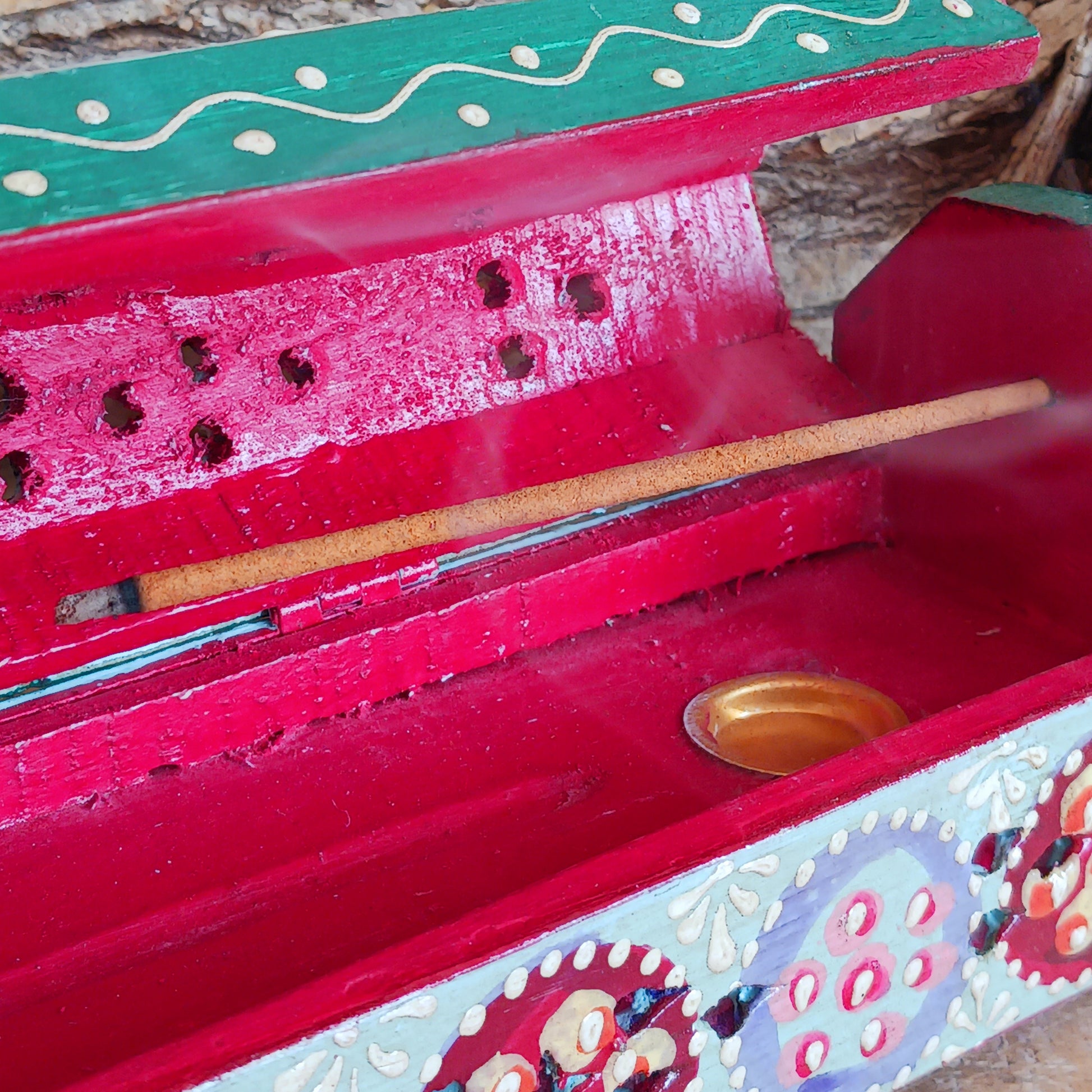 This beautiful turquoise wooden Incense box has been hand painted and has a curved hinged lid. It can accommodate both incense sticks and cones. There is also a place for you to safely store your incense sticks at the bottom on the box.