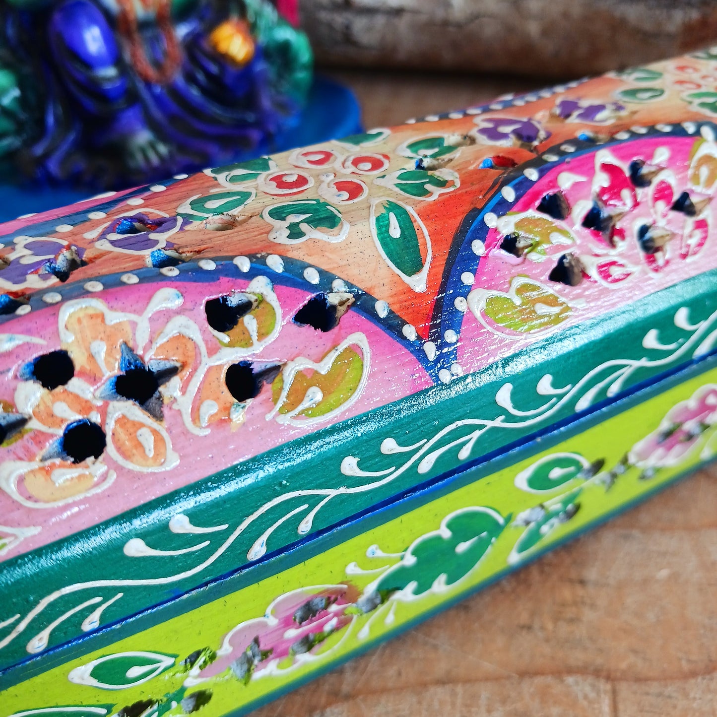 This beautiful pink and green wooden Incense box has been hand painted and has a curved hinged lid. It can accommodate both incense sticks and cones. There is also a place for you to safely store your incense sticks at the bottom on the box.