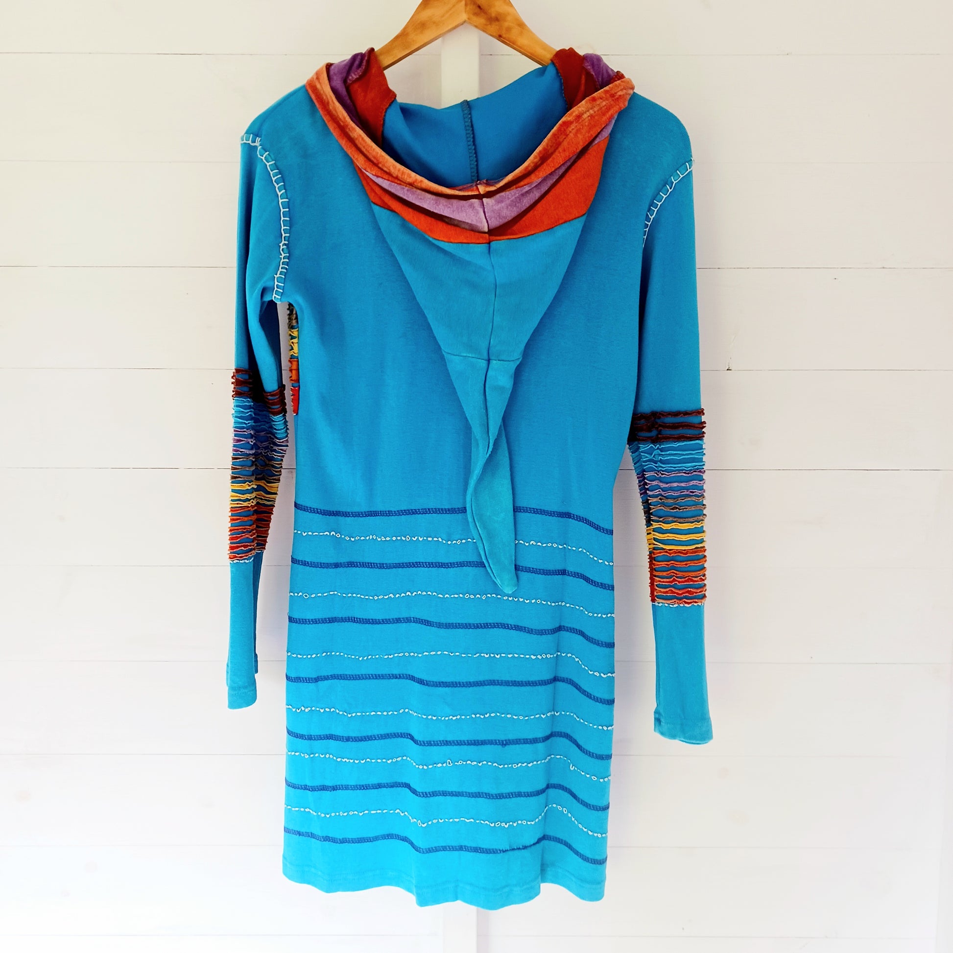 Make a bold statement with this handmade turquoise Pixie Jacket, a striking patchwork coat designed for free spirits and lovers of expressive, bohemian fashion. Crafted in Nepal from soft, stretchy cotton jersey, this longline jacket blends vibrant colours, artistic prints, and intricate detailing into a truly unique outerwear piece.
