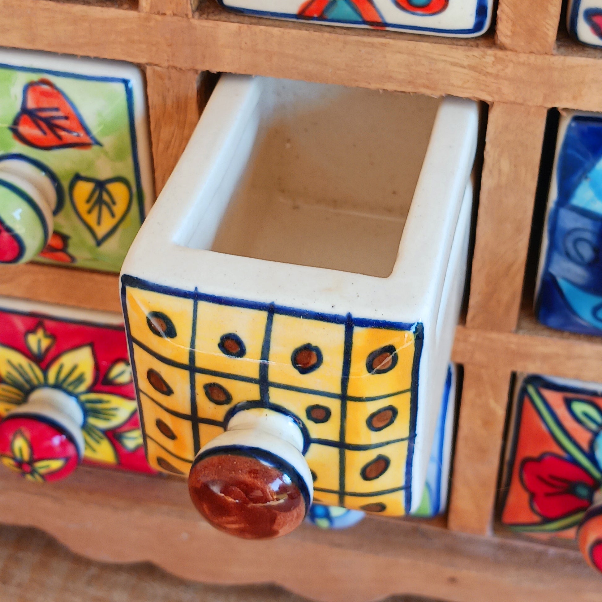 Add a touch of authentic Indian craftsmanship to your home with this Handcrafted Indian Ceramic 16-Drawer Mini Chest. Featuring 16 individually hand-painted ceramic drawers set within a warm wooden frame, this decorative storage cabinet is both practical and beautifully unique.