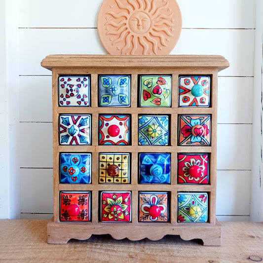 Add a touch of authentic Indian craftsmanship to your home with this Handcrafted Indian Ceramic 16-Drawer Mini Chest. Featuring 16 individually hand-painted ceramic drawers set within a warm wooden frame, this decorative storage cabinet is both practical and beautifully unique.