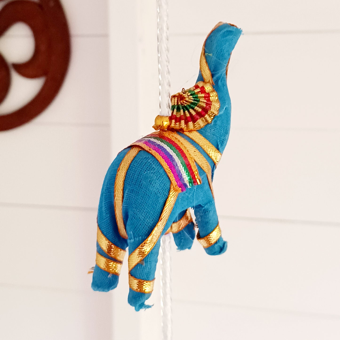 Bring vibrant charm and a touch of global-inspired décor into your home with this beautifully handcrafted stuffed elephant hanging garland. Designed in a traditional tota bell style, this decorative piece features a string of brightly coloured fabric elephants, carefully interspersed with playful beads, mini pom-poms, and delicate jingly bells.