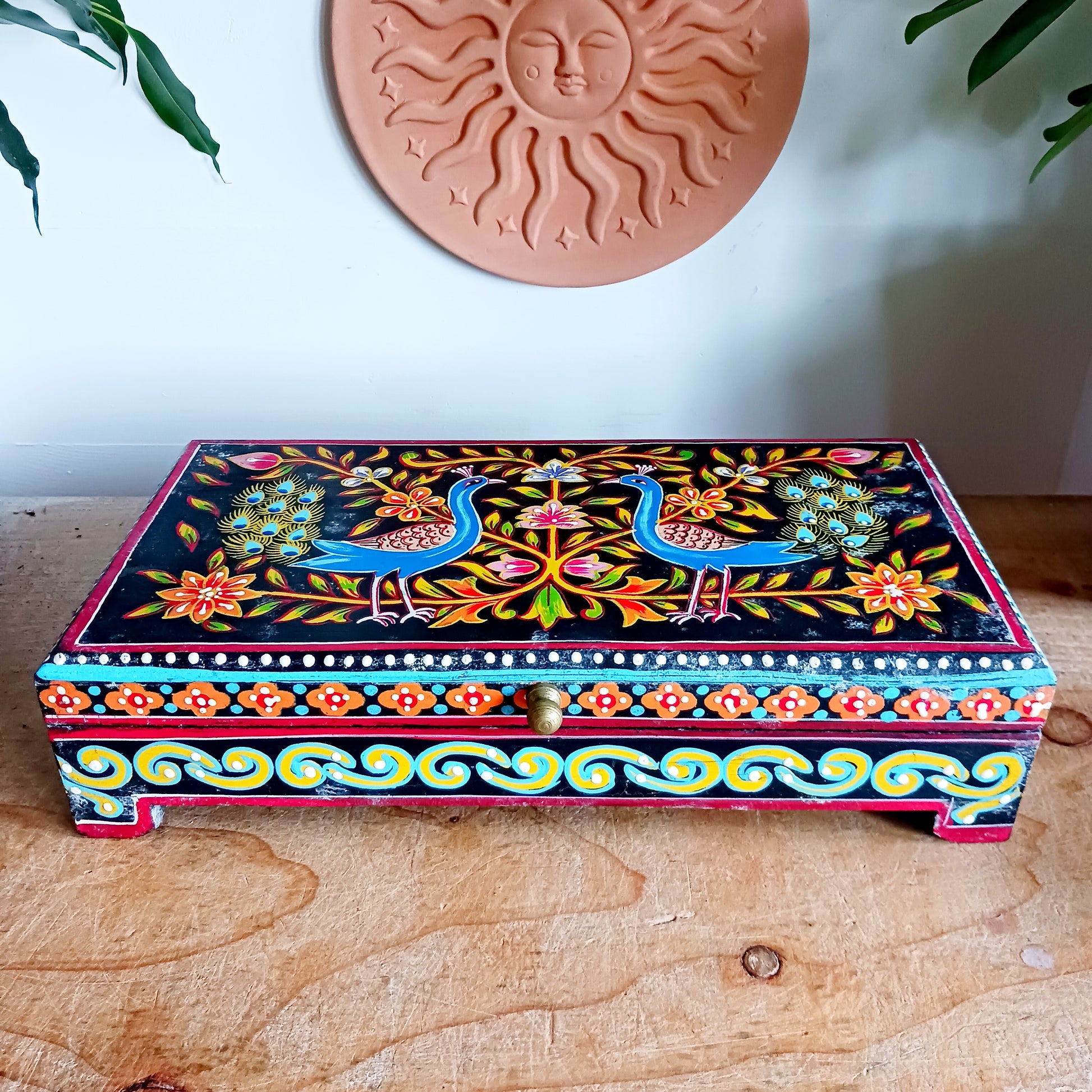 Add a touch of colour, culture, and craftsmanship to your home with this beautifully hand painted mango wood jewellery box. Thoughtfully crafted from sustainable mango wood, this decorative keepsake box features an elegant pair of peacocks framed by intricate florals on the lid and sides.